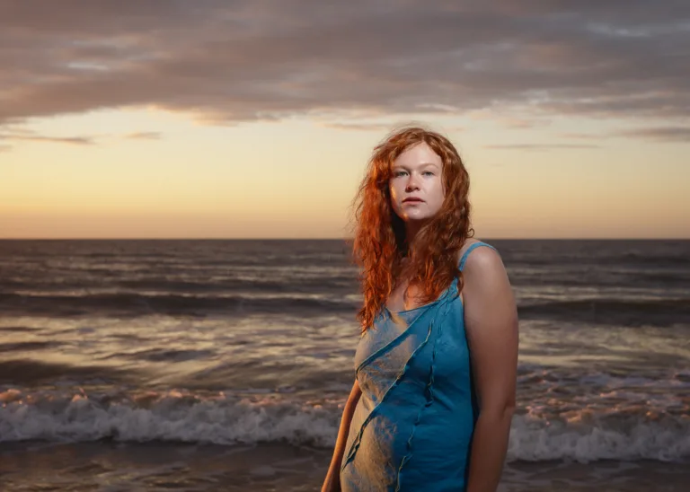 Woman standing by the sea at sunset.
