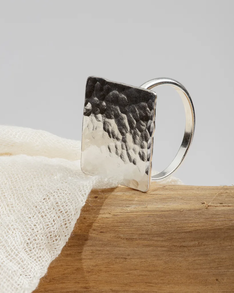 Textured silver ring on fabric and wood