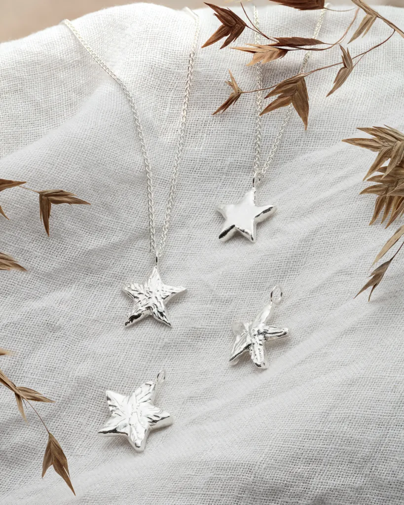 Silver star necklaces on textured fabric background.