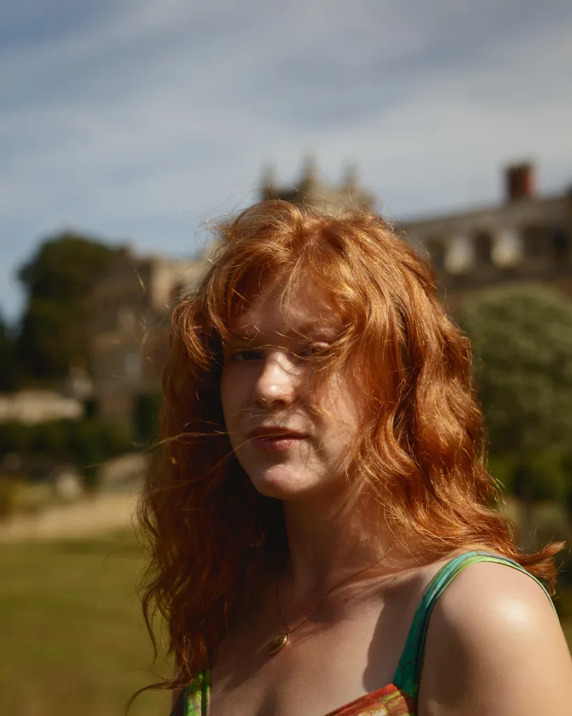 Person with red hair in sunlight, outdoor setting.