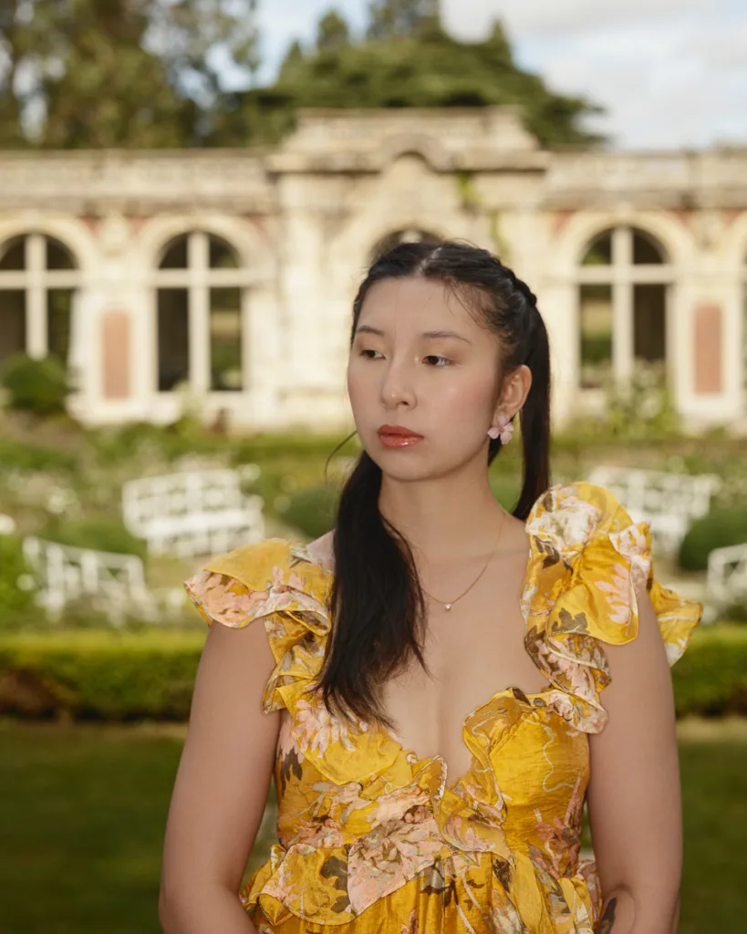 Person in yellow floral dress in garden setting.