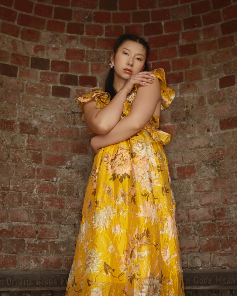 Woman in floral dress against brick wall
