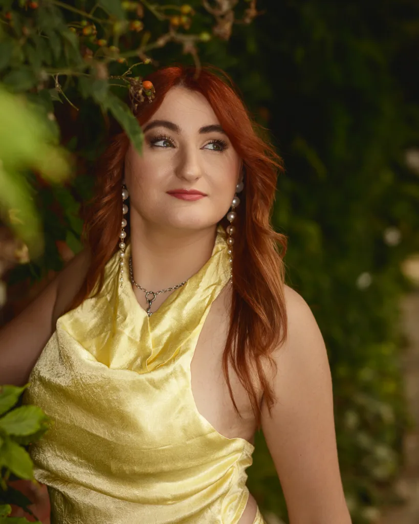 Person with red hair in yellow dress outdoors.