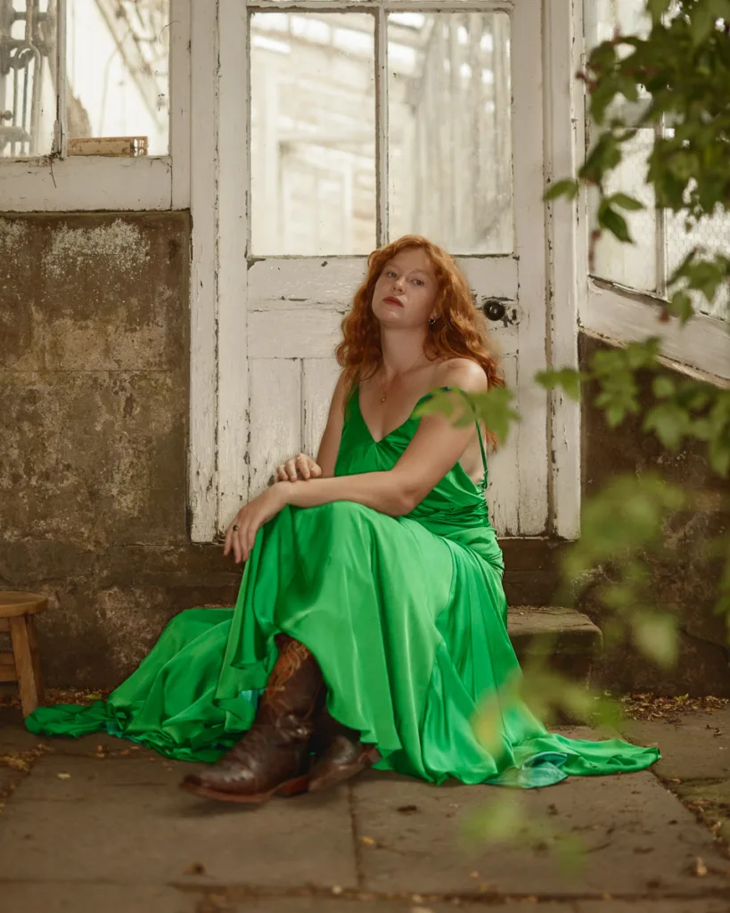 Woman in green dress sitting by rustic door