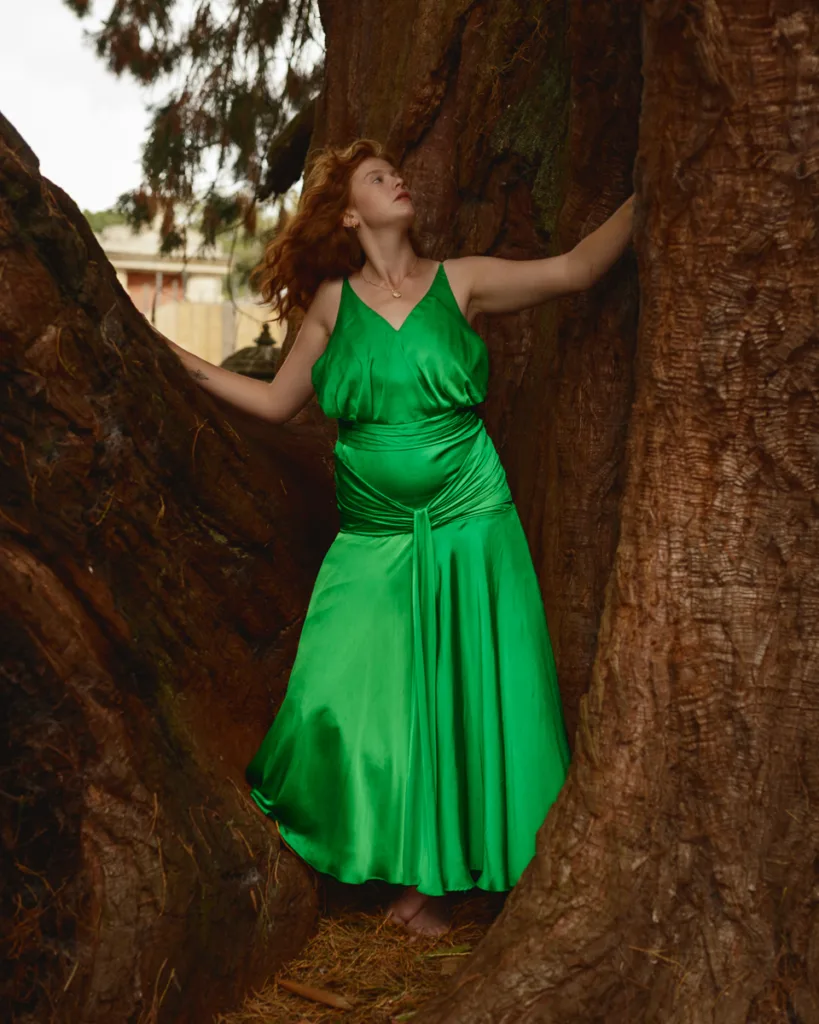 Woman in green dress among large trees