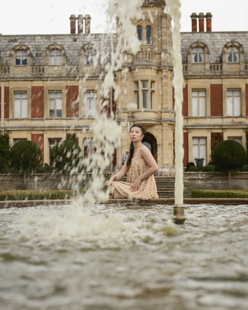 Woman by fountain, historic building in background