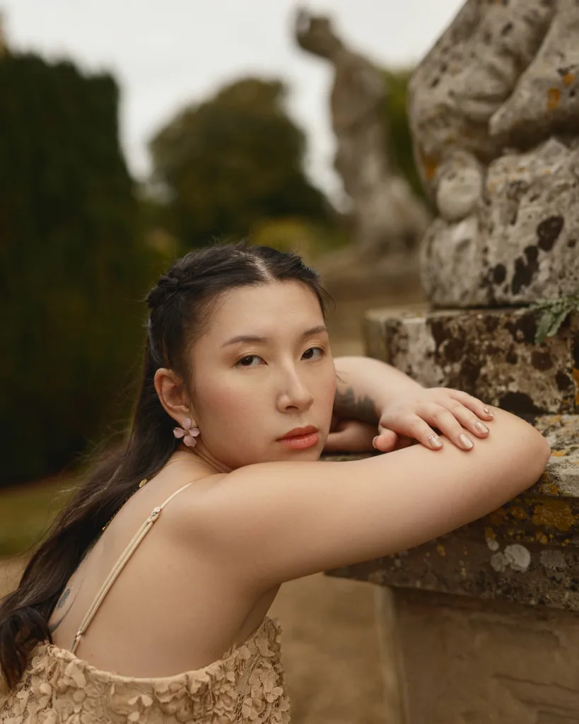 Person leaning on textured stone in garden setting.