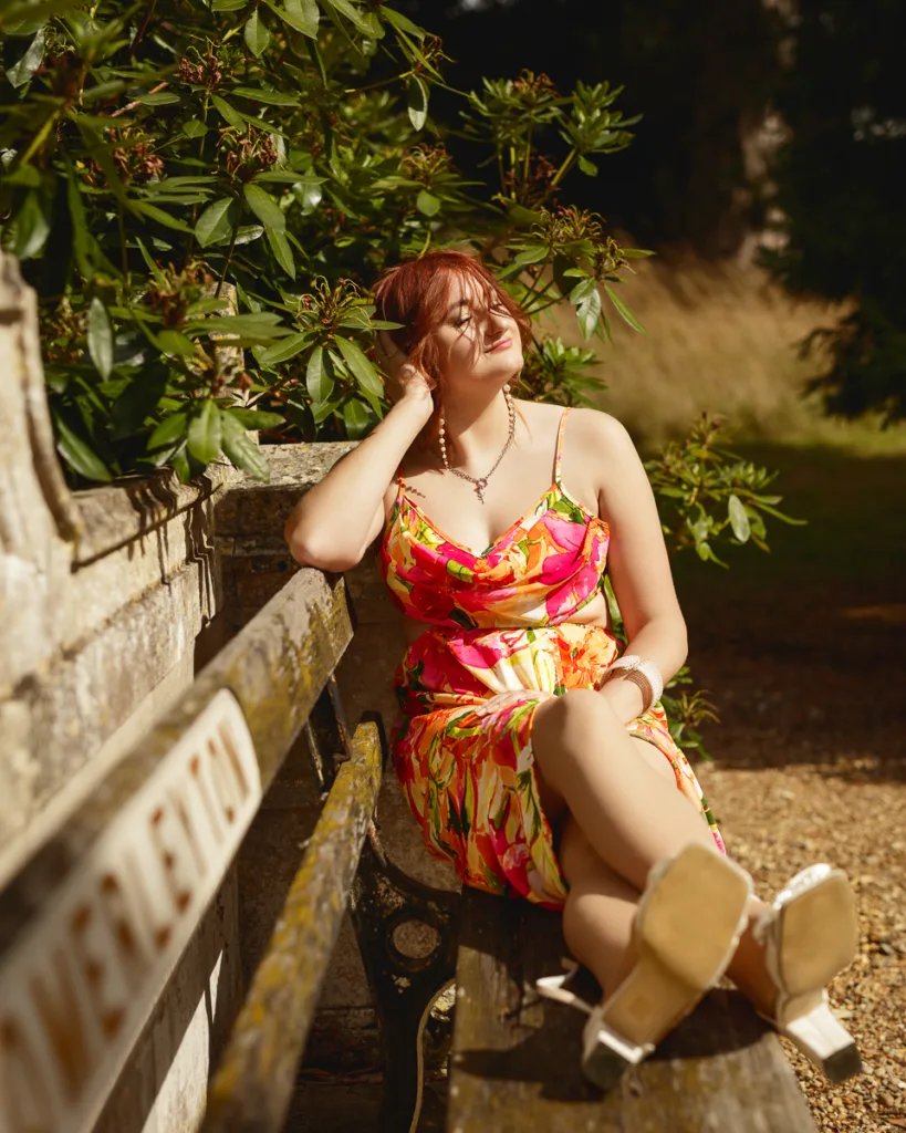Woman relaxing on a bench in floral dress.