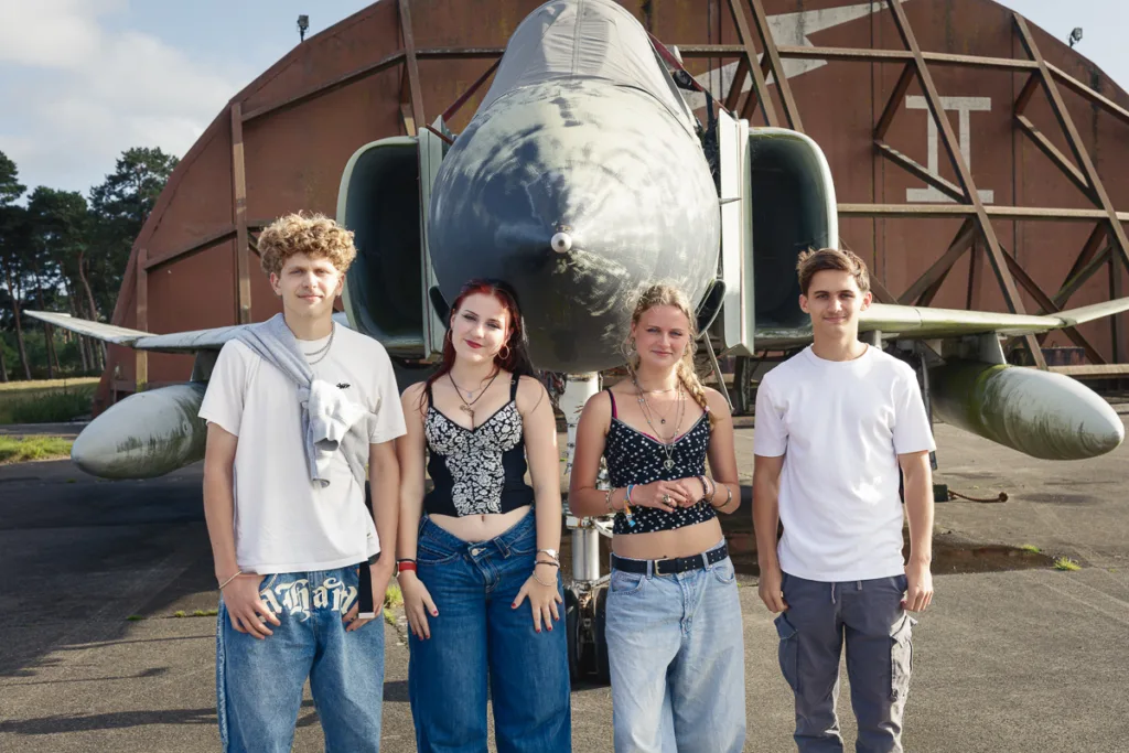 Four people standing in front of a fighter jet.