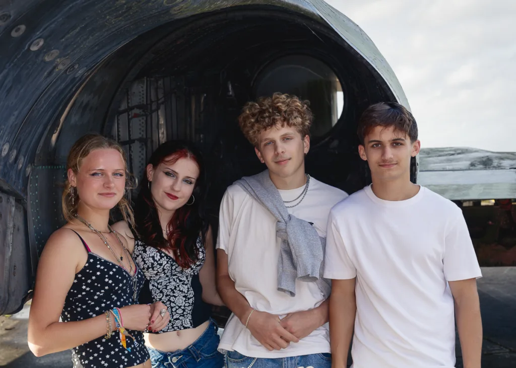 Group of friends standing by aircraft engine.