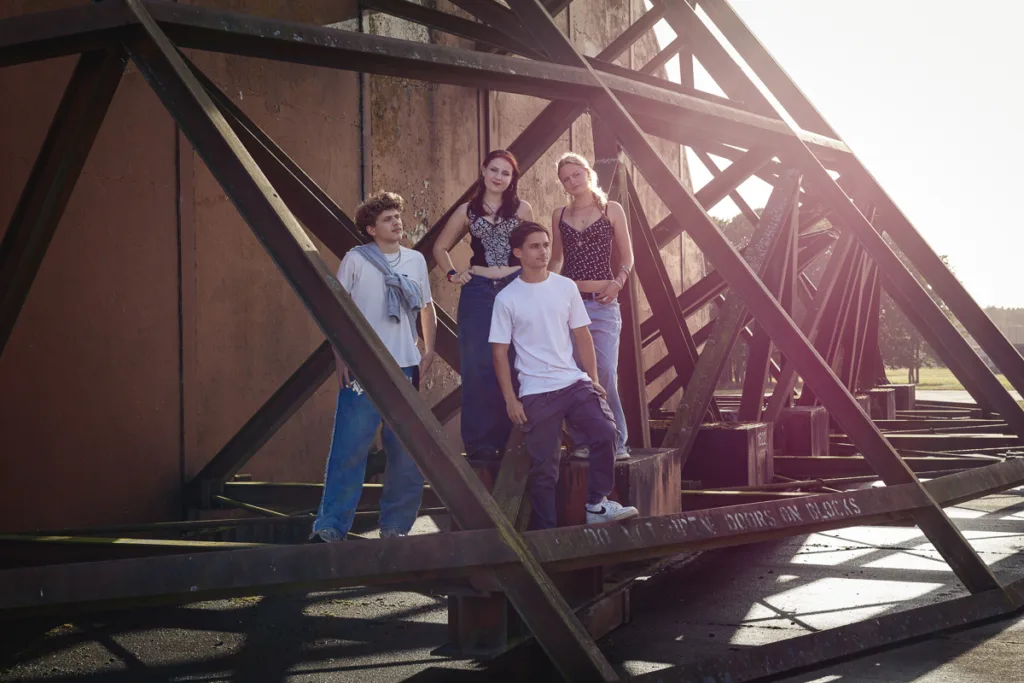 Four people standing on industrial metal structure.