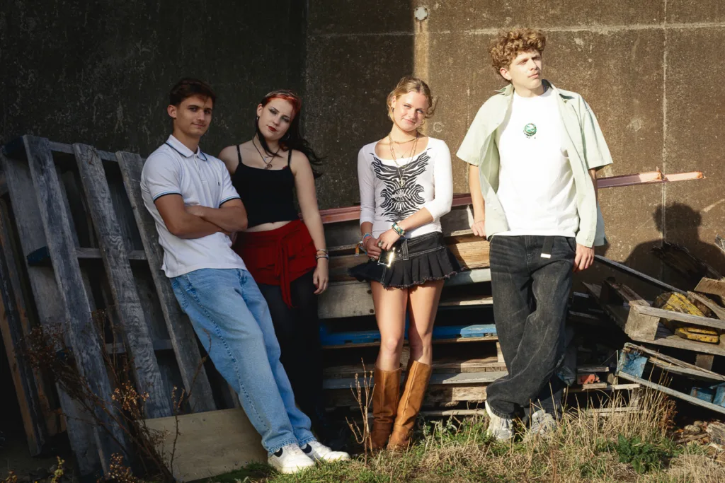 Four young people standing outside on a sunny day.
