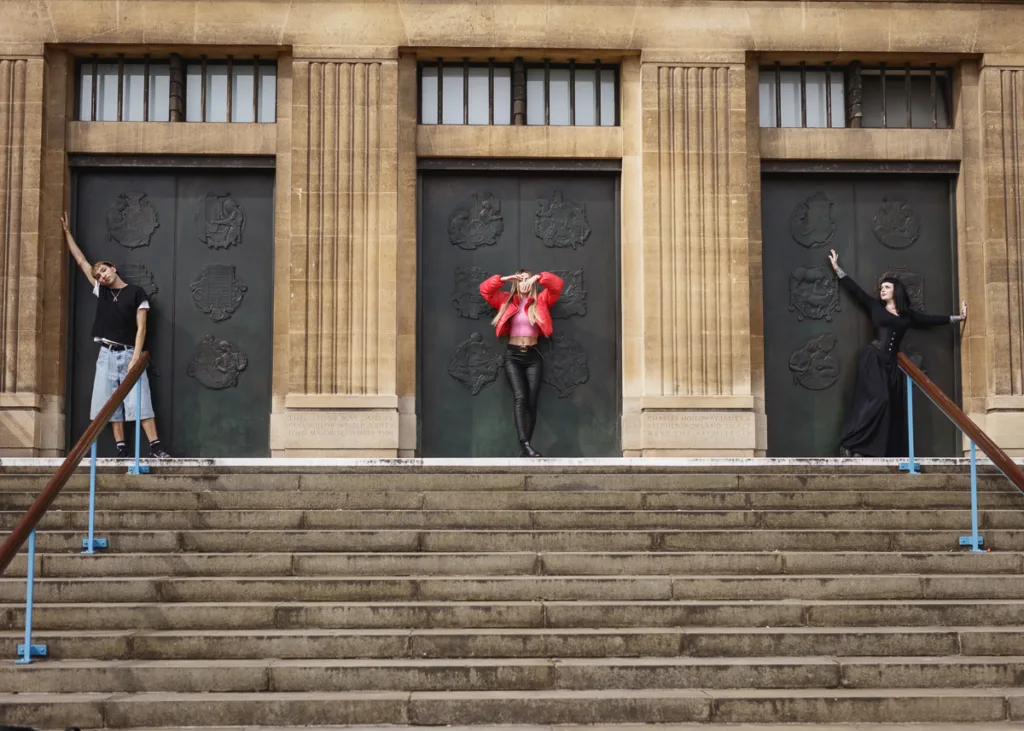 Three models posing on grand stone steps.