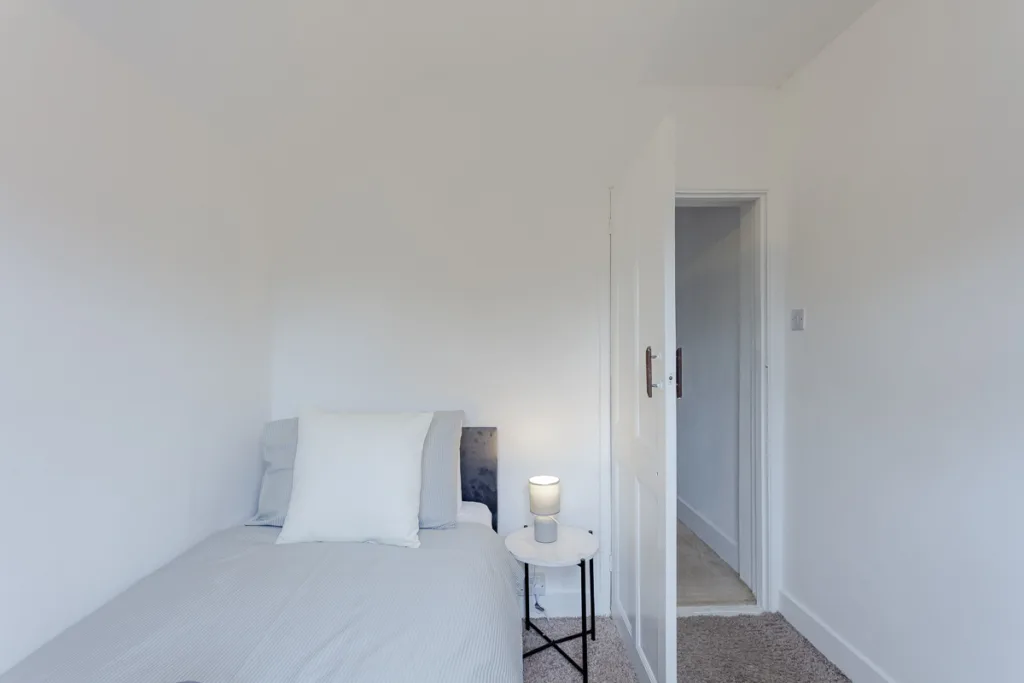 Minimalist bedroom with bed and side table lamp.