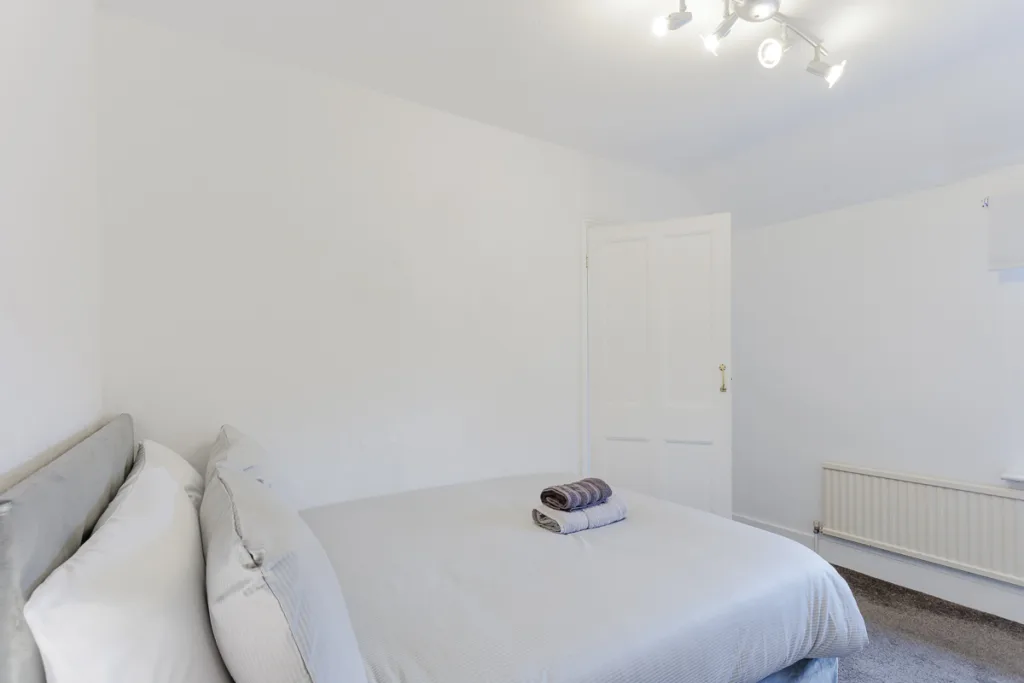 Minimalist white bedroom with double bed and towels.