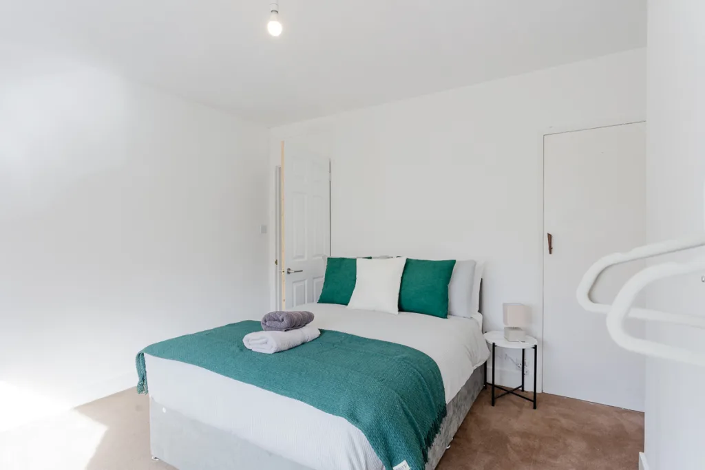 Minimalist bedroom with teal accents and natural light.