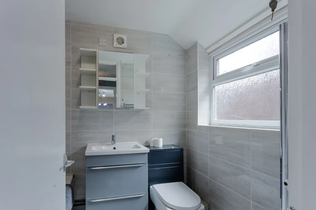 Modern grey bathroom with window and shelves.