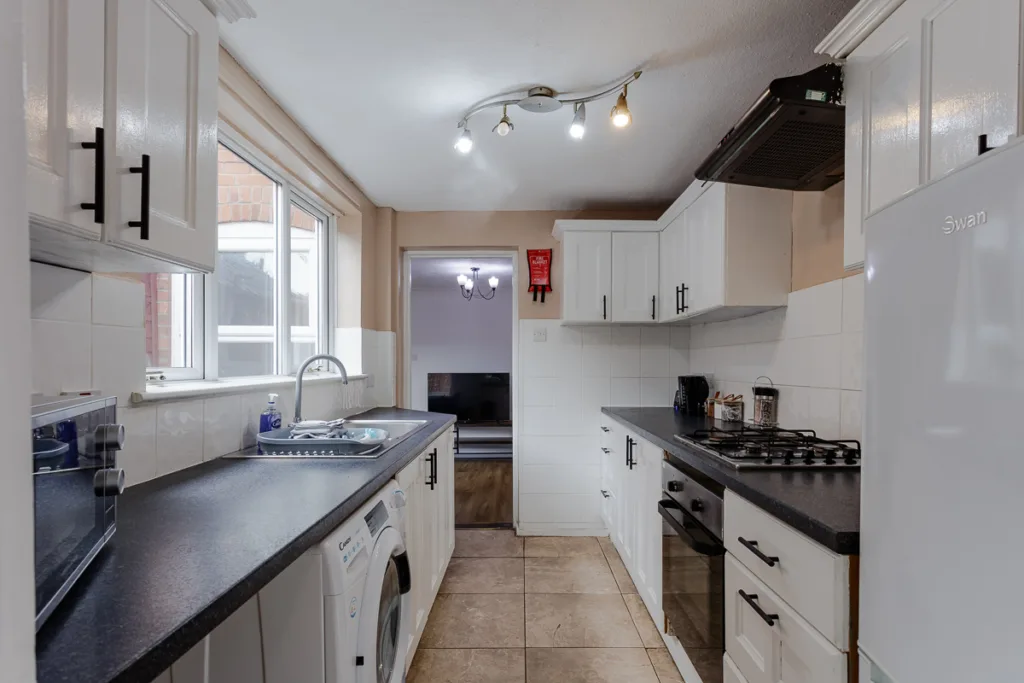 Modern kitchen with white cabinets and appliances.