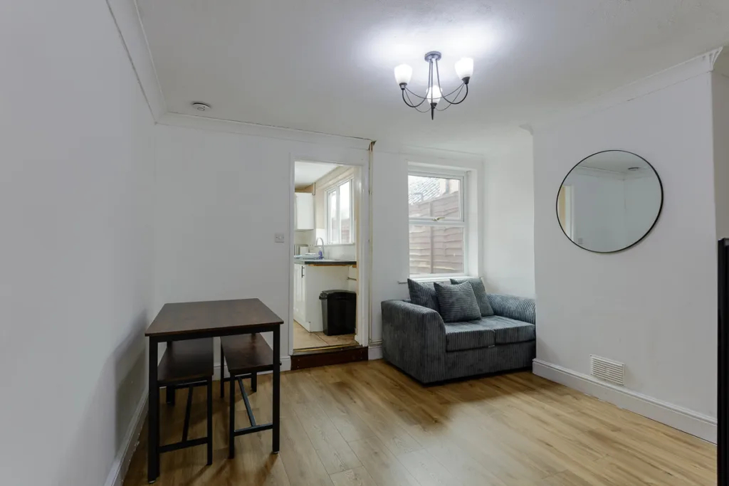 Simple living room with table, sofa, and kitchen view.