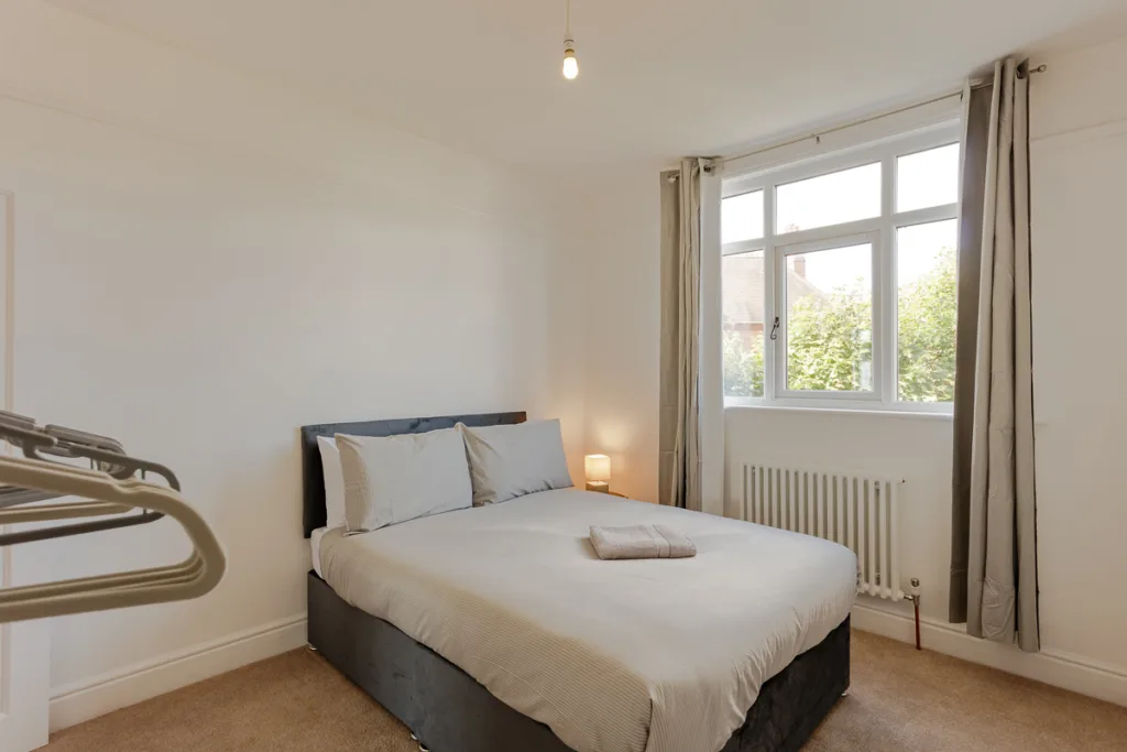 Bright bedroom with double bed and large window.