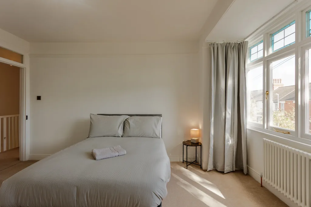 Bright bedroom with double bed and bedside lamp.