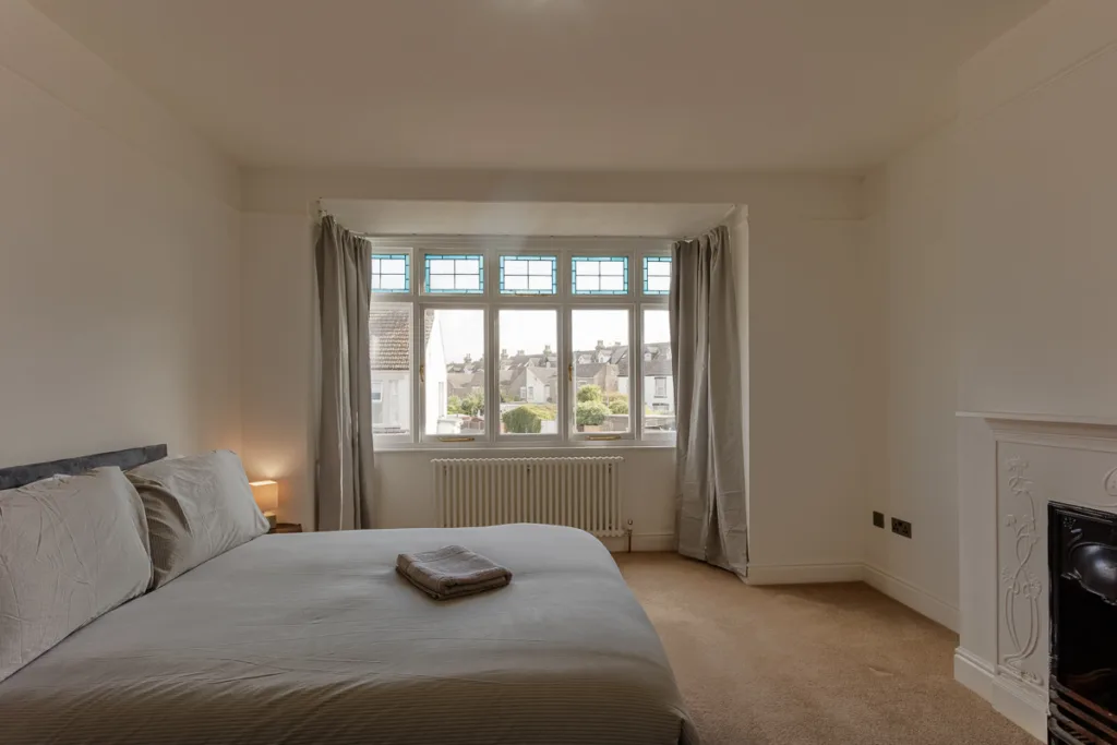Cosy bedroom with large window and bed.