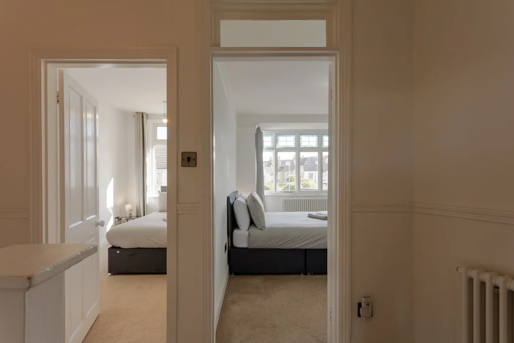 Two adjacent bedrooms with large windows and beds.