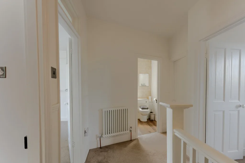 Modern hallway leading to bathroom with radiator