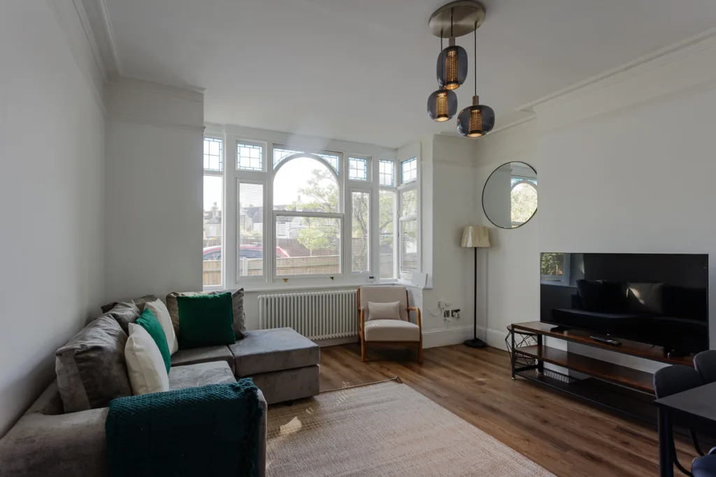Bright living room with sofa, TV, and large windows.