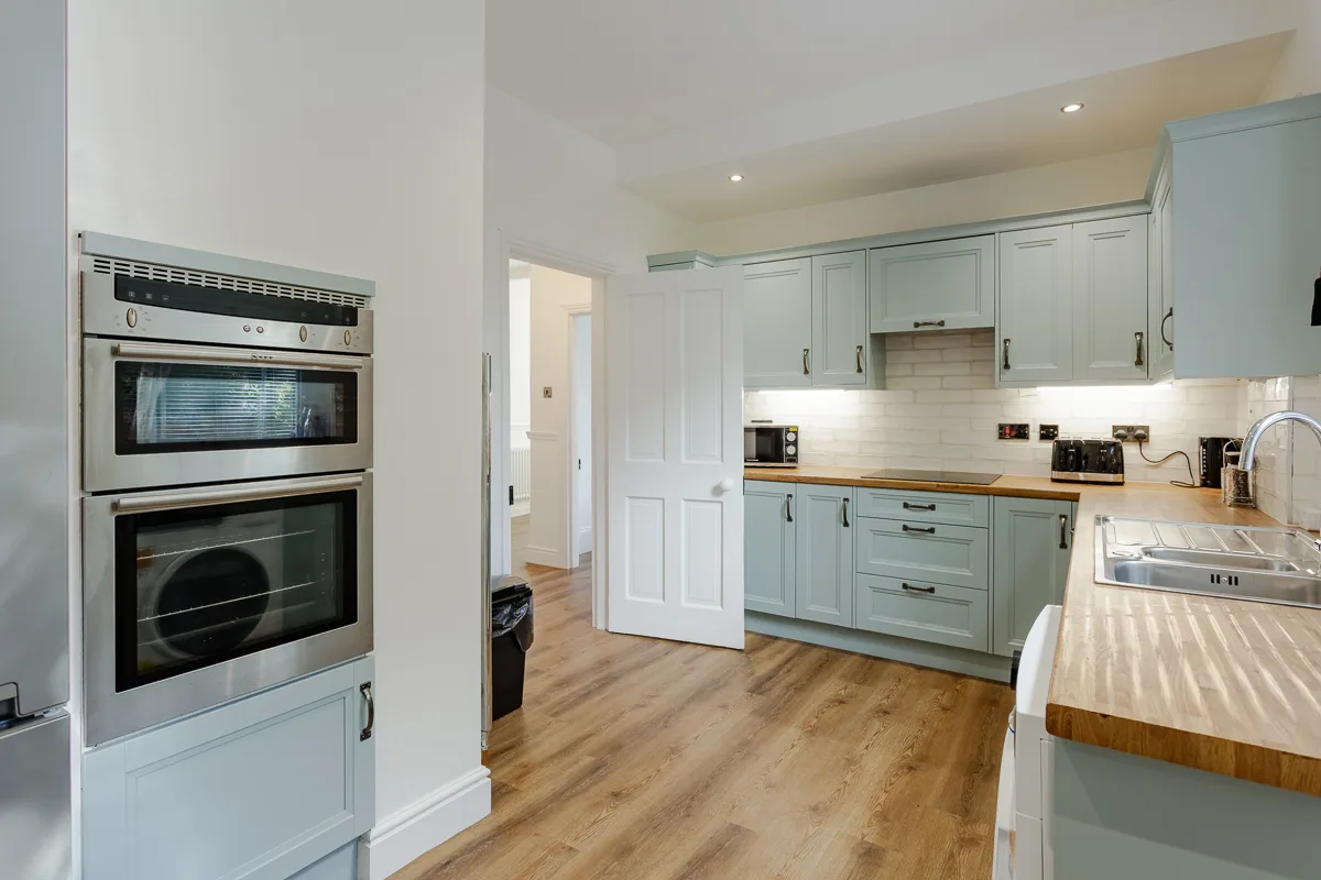 Modern kitchen with wooden floors and light cabinets.