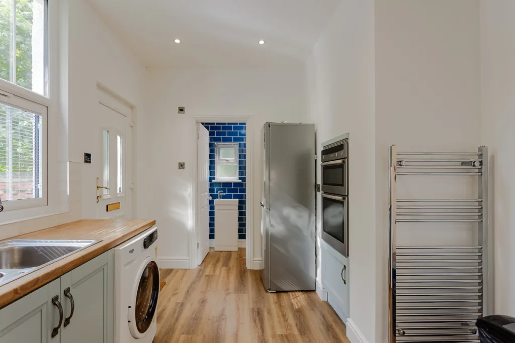 Modern kitchen with blue-tiled bathroom doorway.