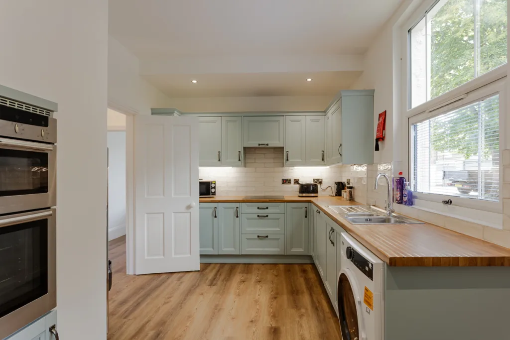 Modern kitchen with wooden flooring and appliances.