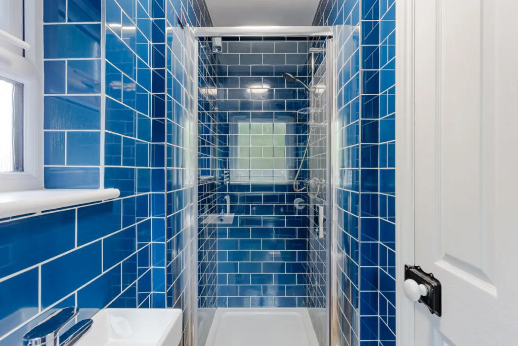 Compact bathroom with blue tiled shower enclosure.