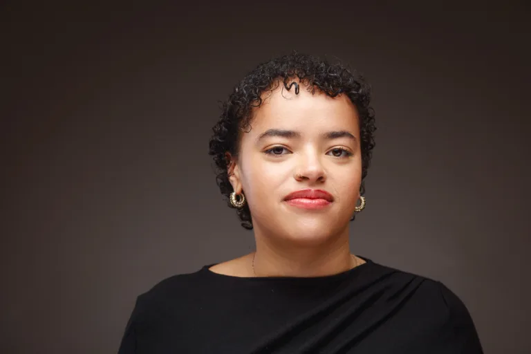 Person with curly hair wearing hoop earrings.