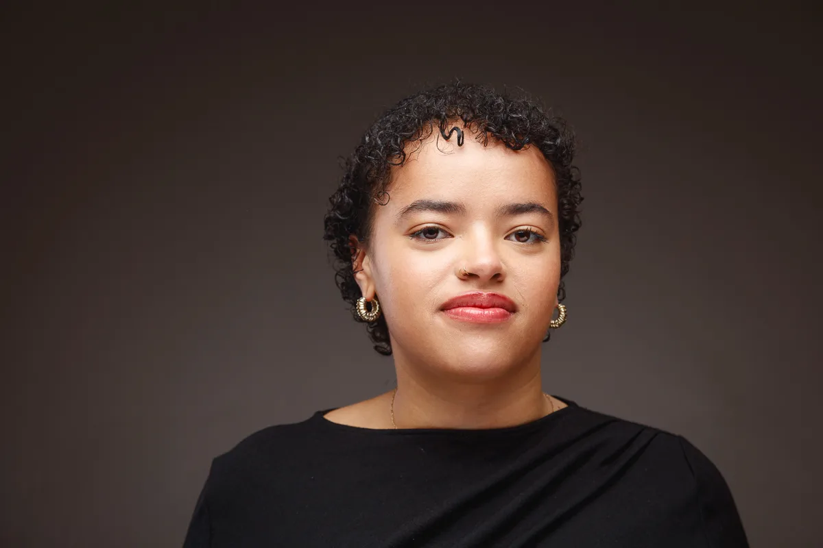 Person with curly hair wearing hoop earrings.