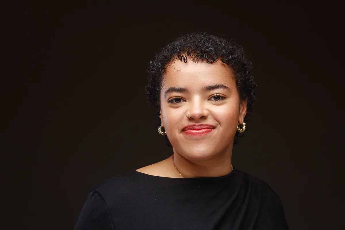Smiling person with curly hair and earrings.