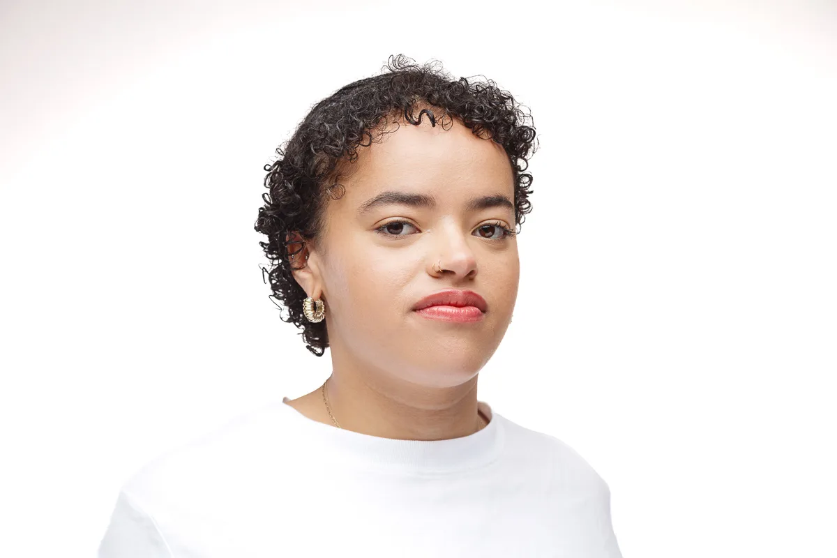Person with curly hair and white shirt smiling.