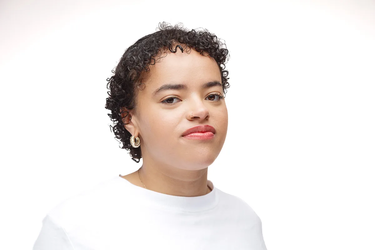 Person with short curly hair and hoop earrings.