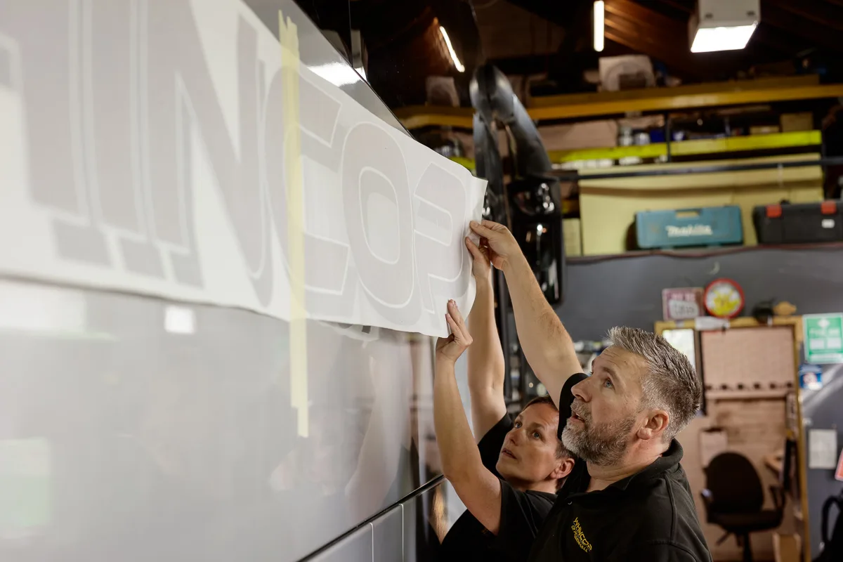 Two people applying a vehicle graphic sticker.
