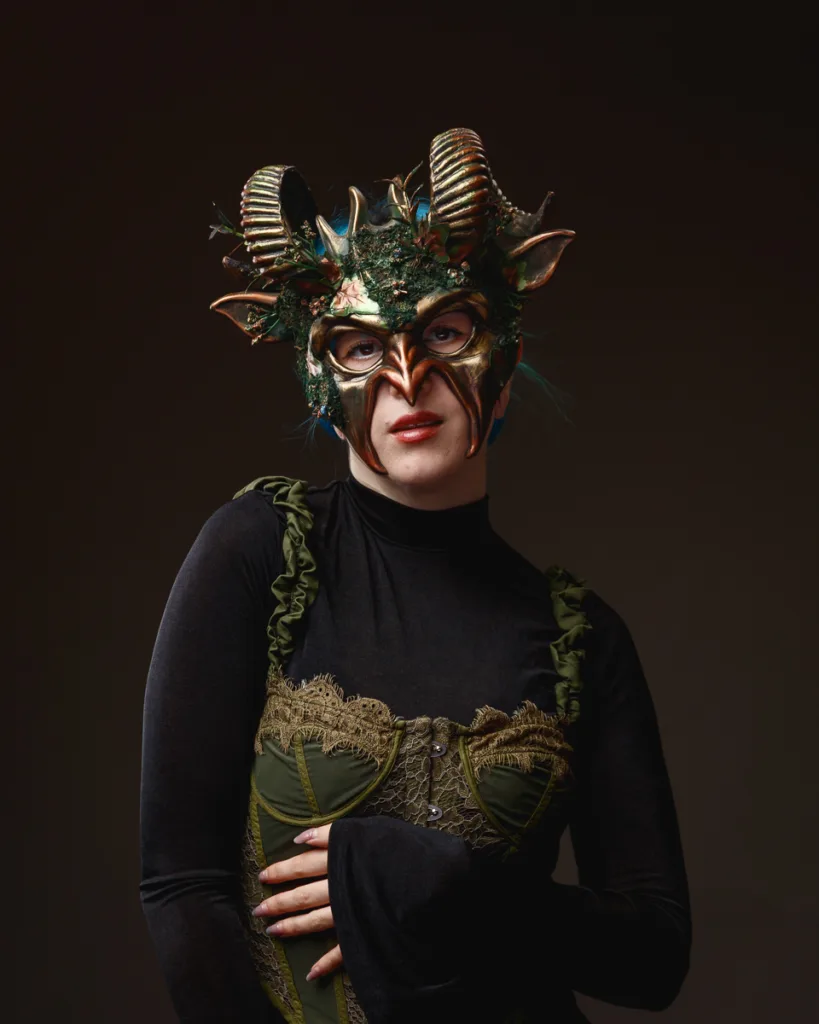 Person wearing intricate horned mask and elegant costume.