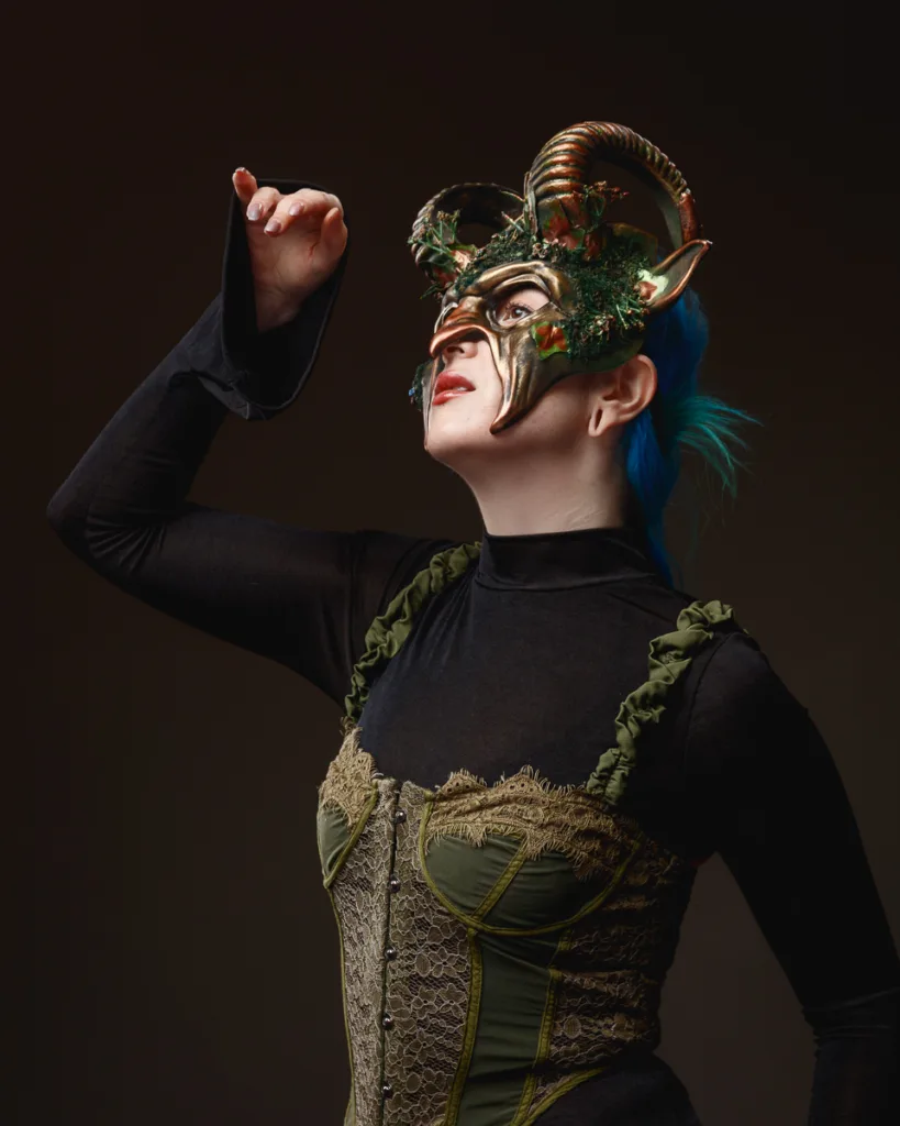 Person in elaborate horned mask and elegant attire.