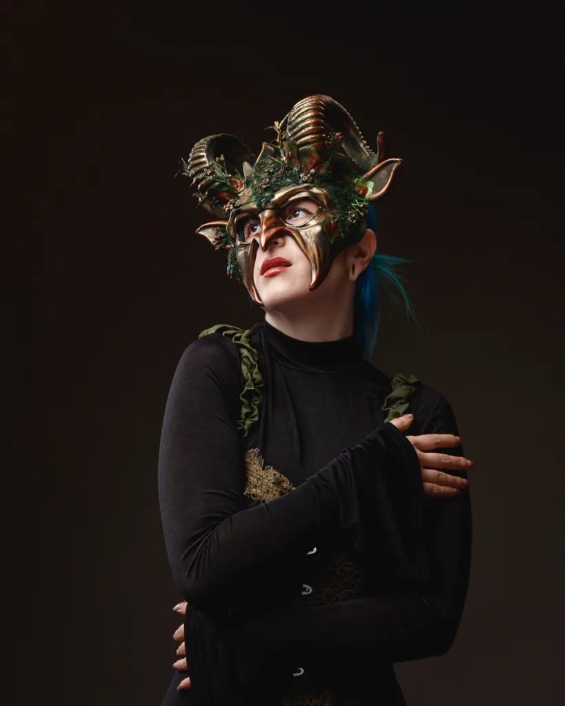 Person wearing an elaborate green horned mask.