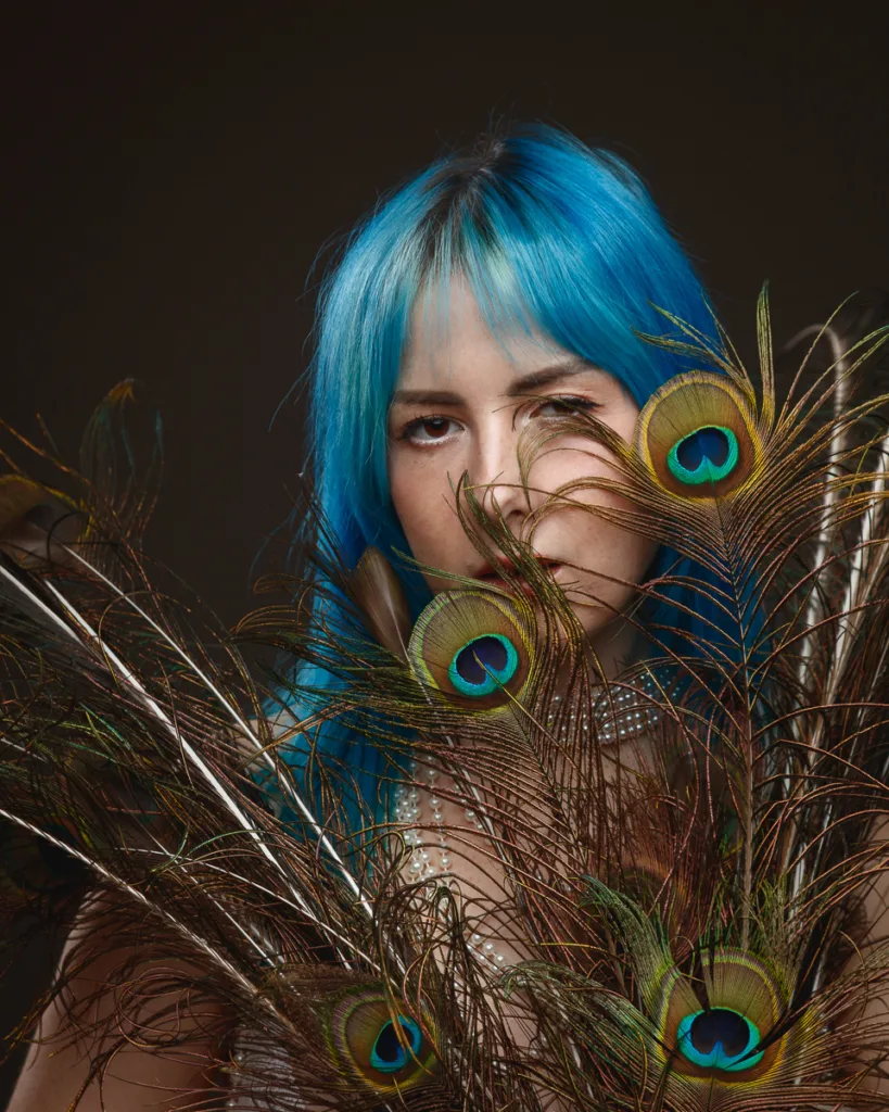 Woman with blue hair and peacock feathers.