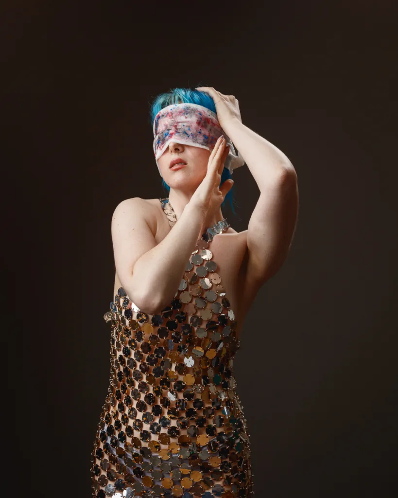 Woman in sequin dress with eyes covered.