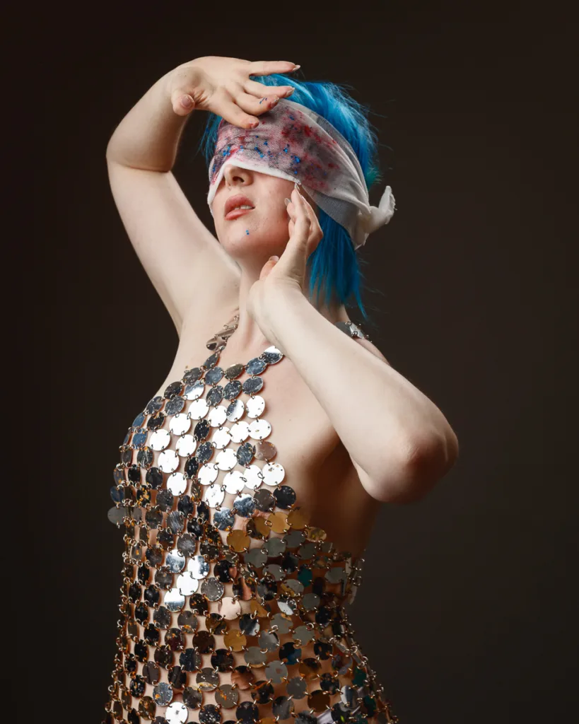 Person posing with blue hair and sequined dress.