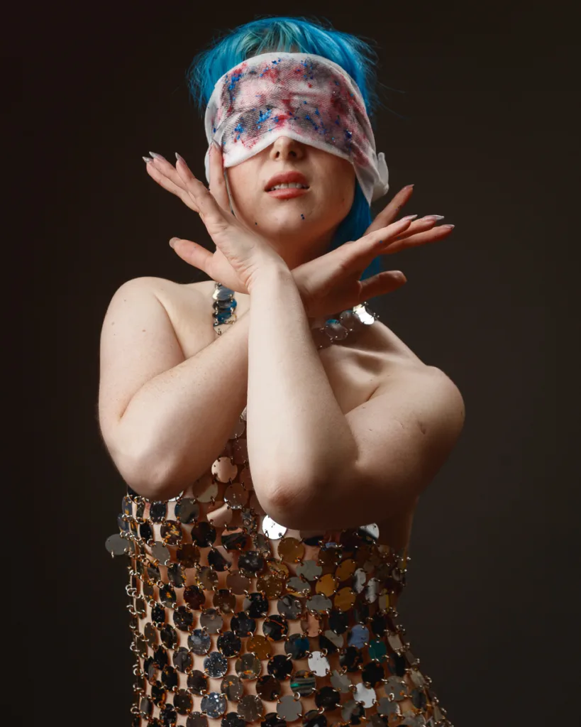 Person with blue hair wearing blindfold, artistic pose