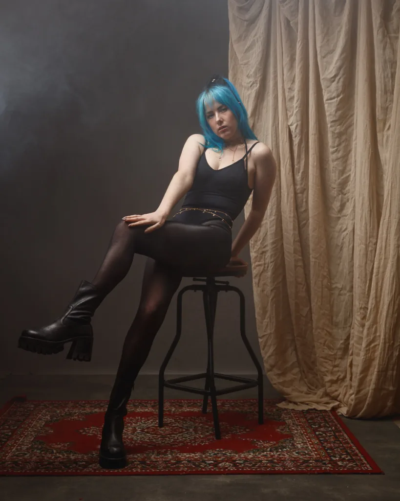 Woman with blue hair sitting on a stool
