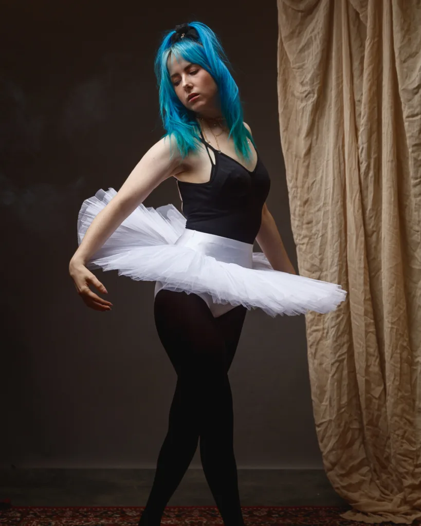 Ballet dancer in white tutu posing gracefully indoors.