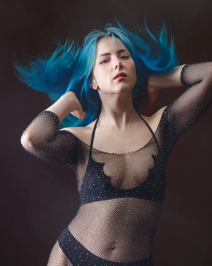 Person with blue hair in black mesh outfit.