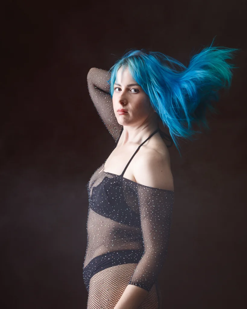 Person with blue hair in sparkly outfit poses.